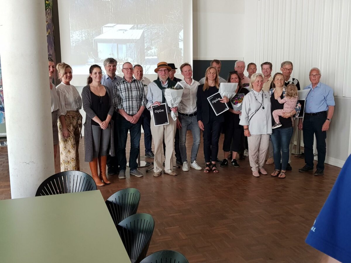 Formand Nis Johan Holm (i midten med hat) med blomster og diplom omgivet af de prisvindende arkitekter og ingeniører. Foto: Domea.dk.