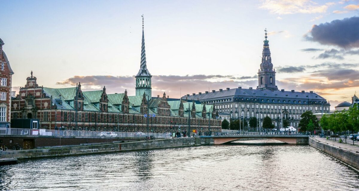 Børsen (tv.) som vi kender den. I skrivende stund er især den del mod Christiansborg (th.) medtaget af branden. Den resterende del er ramt af vand, men ikke decideret af flammerne, oplyser myndighederne. Tårnet og spiret er gået til grunde. Foto: Getty Images