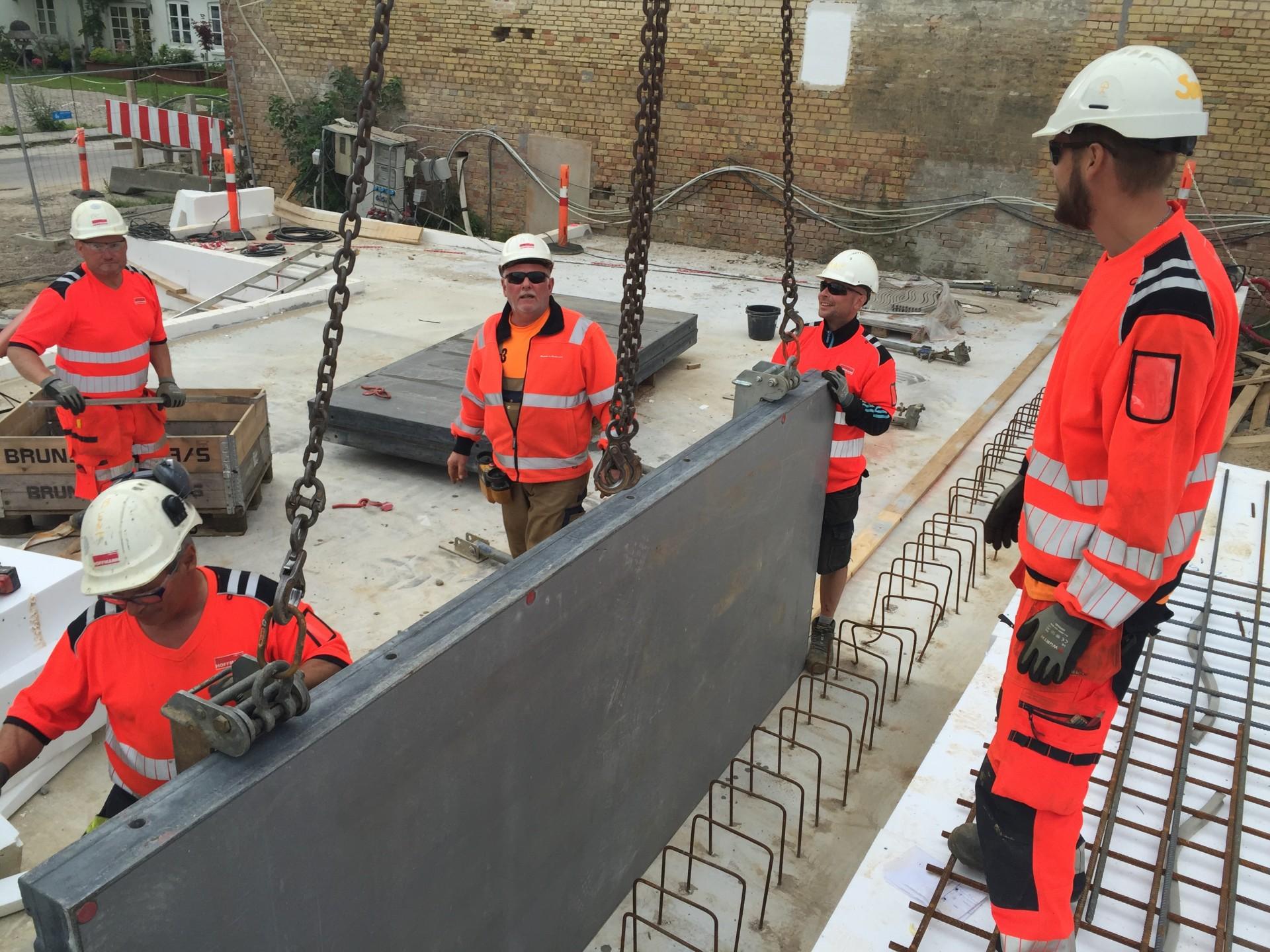 Forskallingsvægge sættes op for at holde den tunge beton i skak.