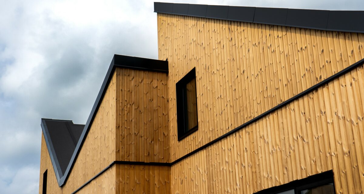 Træbyggeri i 1-1½ etage stræber mod en skyet himmel.