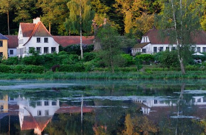 Hvide huse med røde tage ligger på kanten af en sø med høj vandstand.