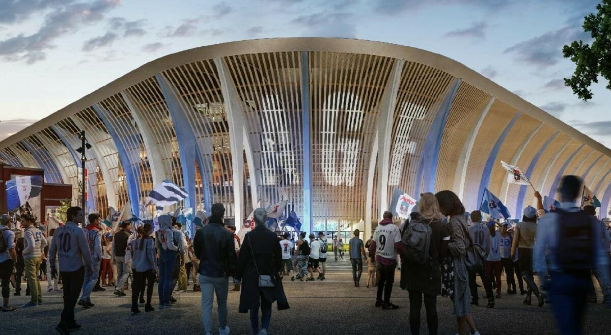 100-vis af AGF-fans sår foran det nye stadion i kongelunden. De har blåhvide flag, hvide fodboldtrøjer. På det buede hjørne af stadion står AGF med mandshøje bogstaver