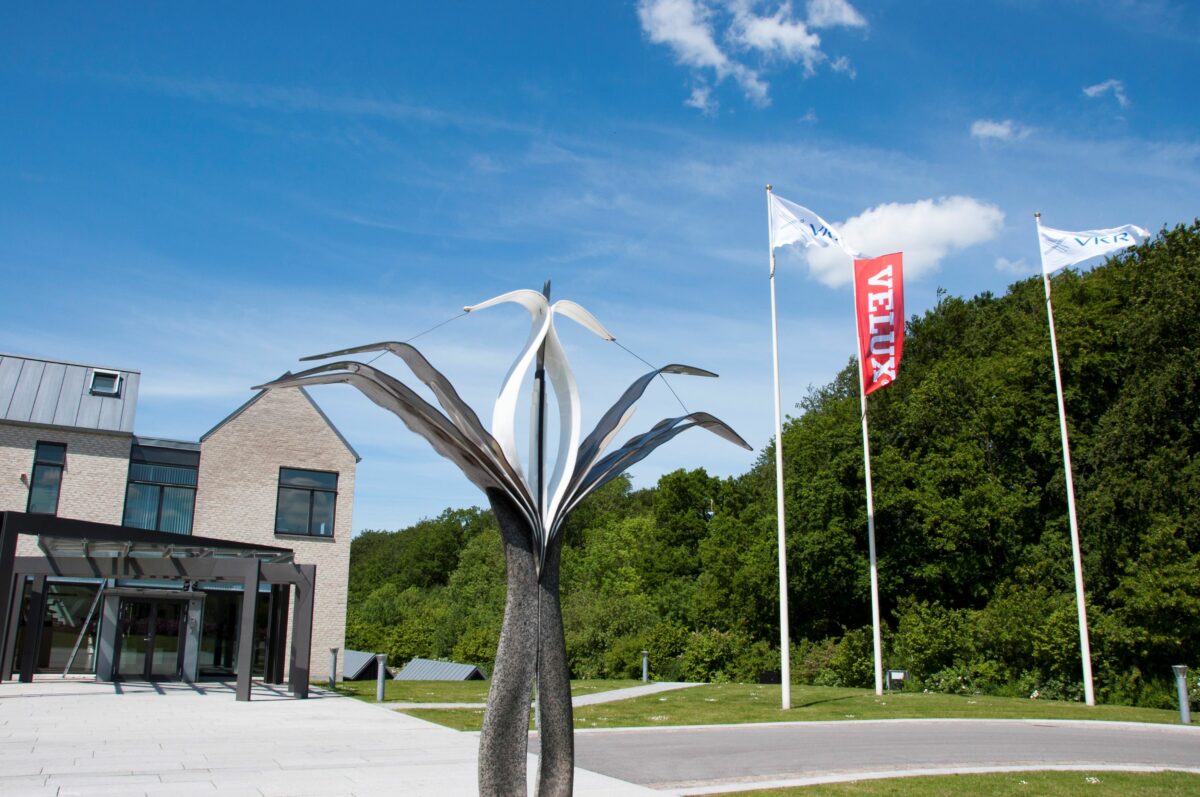 Entré til stor bygning, med skulptur foran.