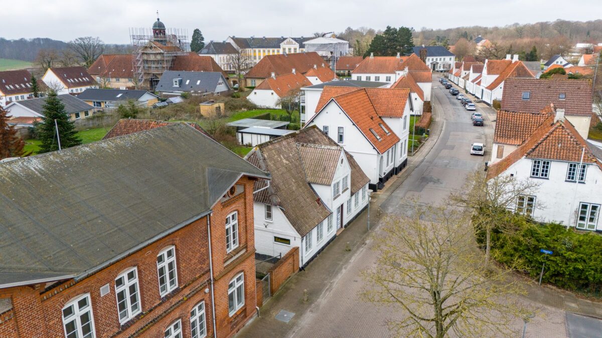 Foto ned langs en gade i Augustenborg. Et enkelt rødt hus i begyndelsen - resten af vejen ned ses primært hvide huse med røde tage