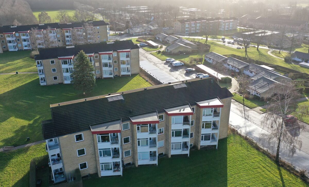 Luftfoto af Søvangen. Til venstre ses tre etageboliger med hvide altaner, der stikker skråt ud fra facaden. Til højre på den anden side af en vej ses de lavere rækkehuse i et plan